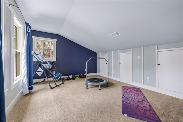 workout room featuring baseboards, carpet, lofted ceiling, and visible vents