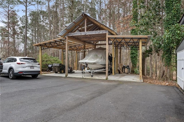 view of car parking with a detached carport and aphalt driveway