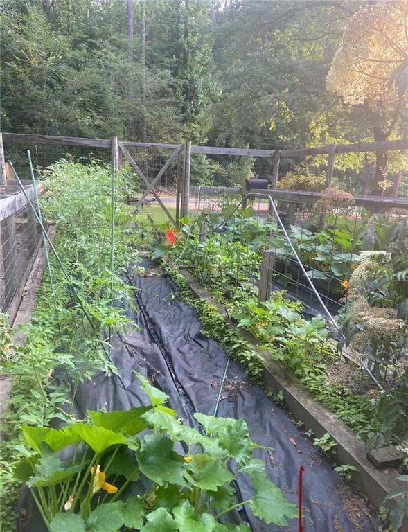 exterior details featuring a view of trees, fence, and a vegetable garden
