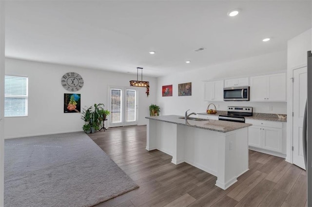 kitchen with white cabinetry, appliances with stainless steel finishes, a kitchen island with sink, and pendant lighting