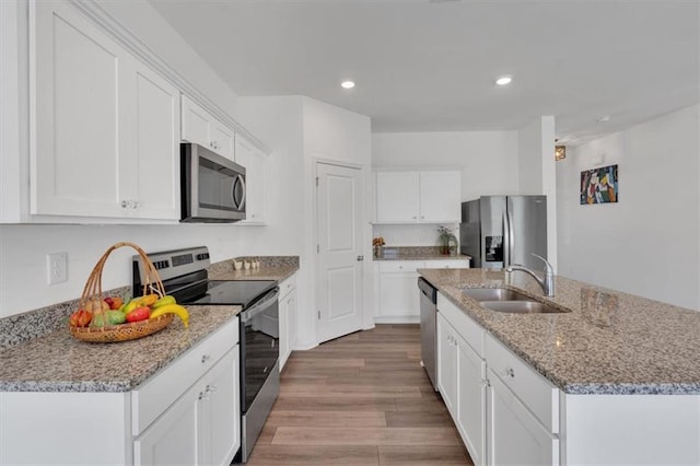 kitchen with sink, white cabinetry, a center island with sink, appliances with stainless steel finishes, and light hardwood / wood-style floors