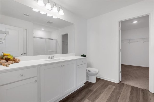 bathroom featuring vanity, hardwood / wood-style flooring, toilet, and walk in shower