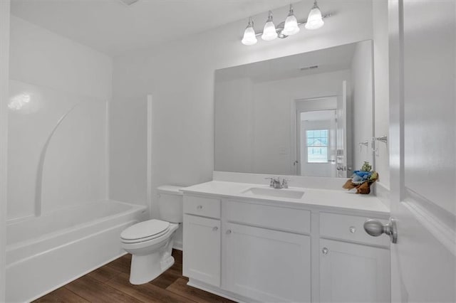 full bathroom featuring hardwood / wood-style flooring, vanity, washtub / shower combination, and toilet