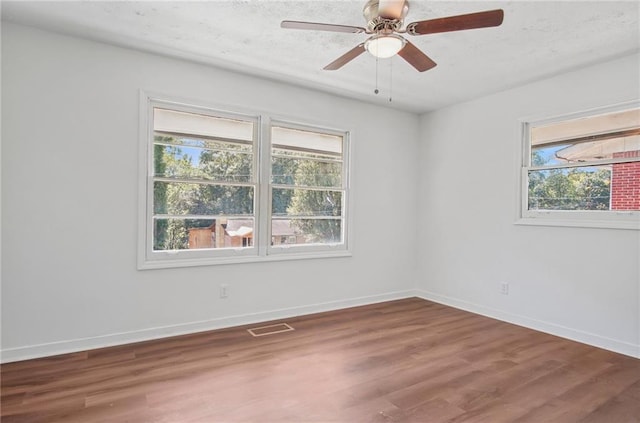 spare room featuring ceiling fan, a healthy amount of sunlight, and wood-type flooring