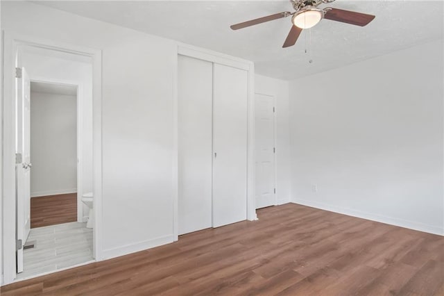 unfurnished bedroom with a closet, light wood-type flooring, ensuite bathroom, and ceiling fan