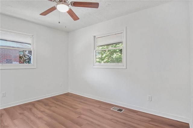 empty room featuring a textured ceiling, light hardwood / wood-style flooring, and ceiling fan