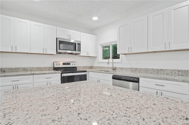 kitchen featuring light stone counters, sink, white cabinets, and appliances with stainless steel finishes