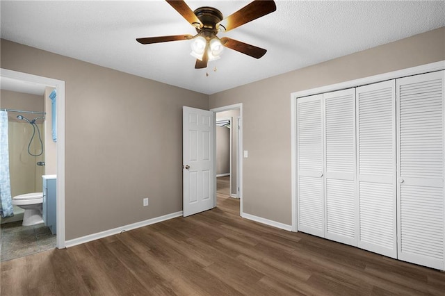 unfurnished bedroom featuring dark wood-type flooring, a textured ceiling, connected bathroom, ceiling fan, and a closet