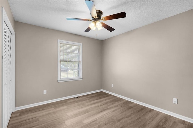 unfurnished bedroom featuring a textured ceiling, light wood-type flooring, ceiling fan, and a closet