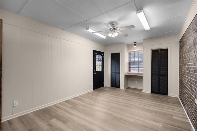 spare room featuring light hardwood / wood-style floors, brick wall, and ceiling fan