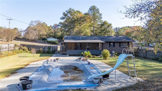 view of swimming pool with a water slide, a sunroom, and a yard