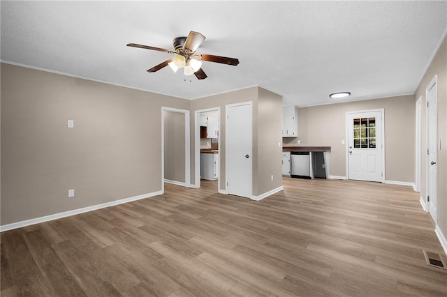 unfurnished living room featuring ornamental molding, light hardwood / wood-style flooring, a textured ceiling, and ceiling fan