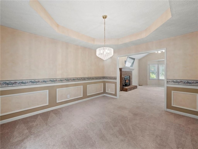 4654 Fox Forrest Dr, Flowery Branch, GA 30542 - empty room featuring a chandelier, carpet, a wainscoted wall, a fireplace, and a raised ceiling