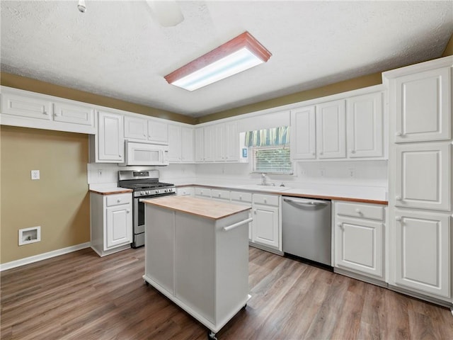4654 Fox Forrest Dr, Flowery Branch, GA 30542 - kitchen featuring appliances with stainless steel finishes, a sink, white cabinets, light wood-style floors, and baseboards
