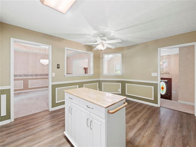 4654 Fox Forrest Dr, Flowery Branch, GA 30542 - kitchen with ceiling fan, white cabinetry, light wood-style flooring, wainscoting, and a center island