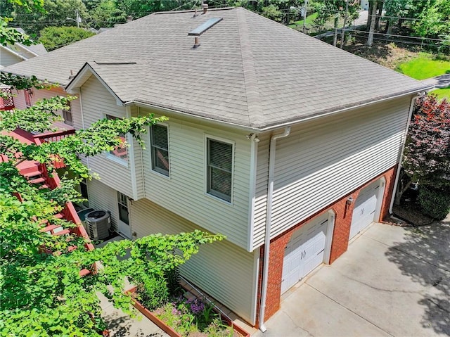 4654 Fox Forrest Dr, Flowery Branch, GA 30542 - view of side of property with a shingled roof, central AC unit, concrete driveway, brick siding, and an attached garage