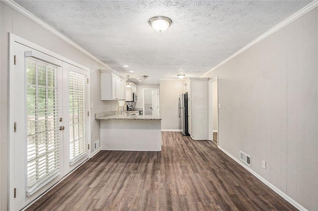 637 Carlouetta Rd SW, Mableton, GA 30126 - kitchen with dark wood-type flooring, a peninsula, freestanding refrigerator, ornamental molding, and white cabinetry