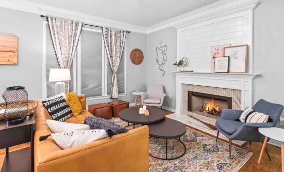 living room with a fireplace, ornamental molding, and wood-type flooring