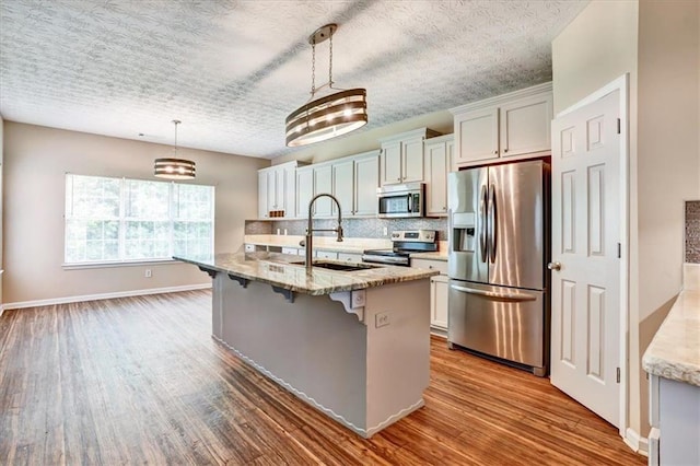 501 Barhams Ridge Dr, Mcdonough, GA 30252 - kitchen with a kitchen breakfast bar, wood finished floors, a sink, decorative backsplash, and stainless steel appliances
