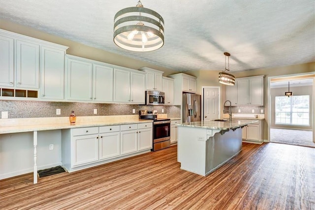 501 Barhams Ridge Dr, Mcdonough, GA 30252 - kitchen featuring a kitchen breakfast bar, a textured ceiling, tasteful backsplash, light wood-style floors, and appliances with stainless steel finishes