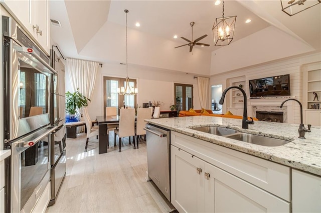 5960 Overlook Club Cir, Suwanee, GA 30024 - kitchen with appliances with stainless steel finishes, a chandelier, open floor plan, a premium fireplace, and white cabinets