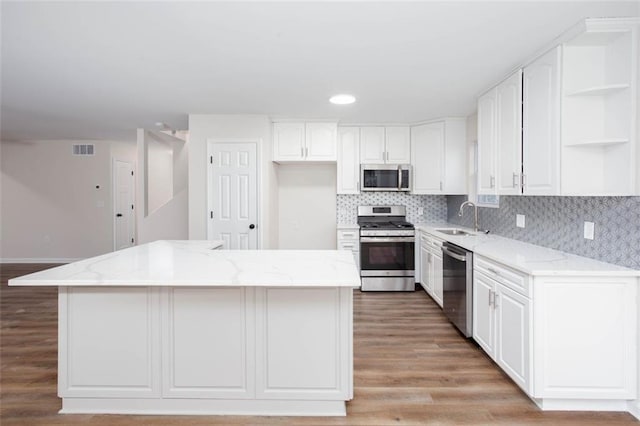 kitchen featuring light stone countertops, a center island, sink, and appliances with stainless steel finishes