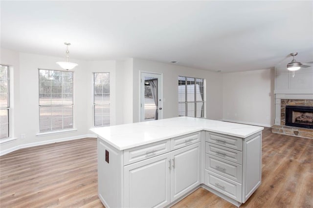 kitchen featuring decorative light fixtures, a fireplace, ceiling fan, a kitchen island, and plenty of natural light