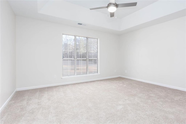 carpeted empty room featuring a raised ceiling and ceiling fan