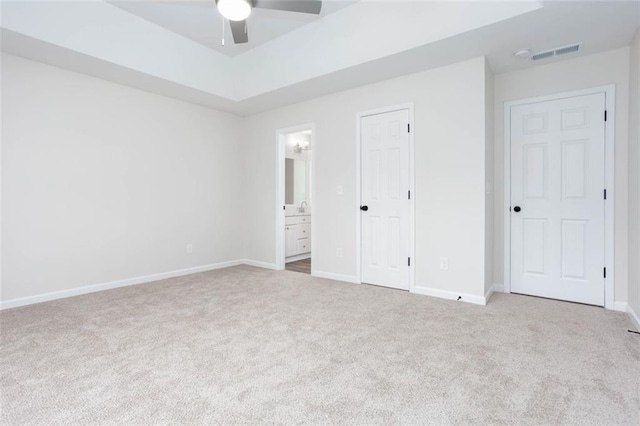 unfurnished bedroom featuring ceiling fan, light colored carpet, and connected bathroom