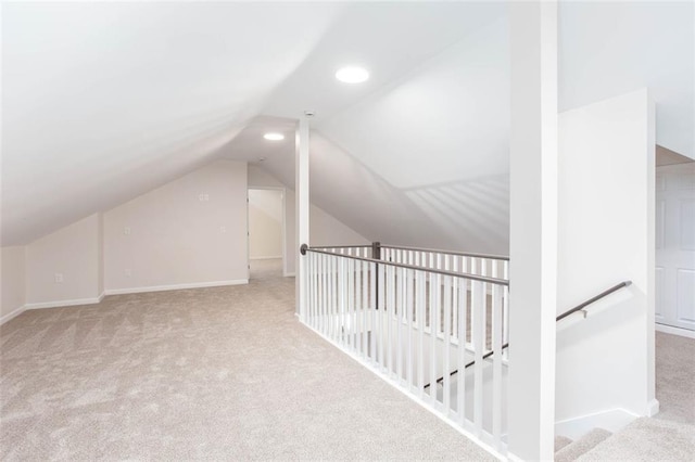 bonus room with vaulted ceiling and light colored carpet