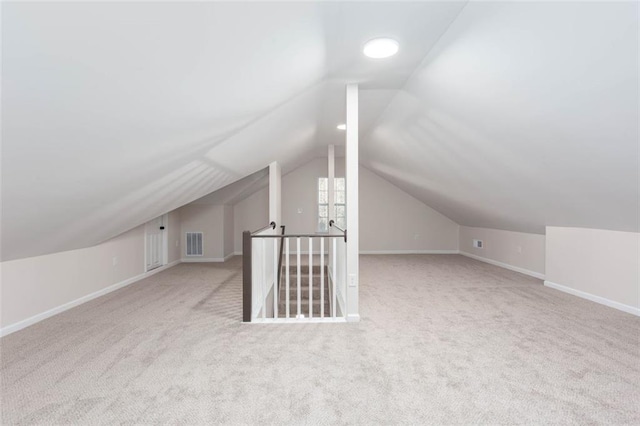 bonus room with vaulted ceiling and light carpet