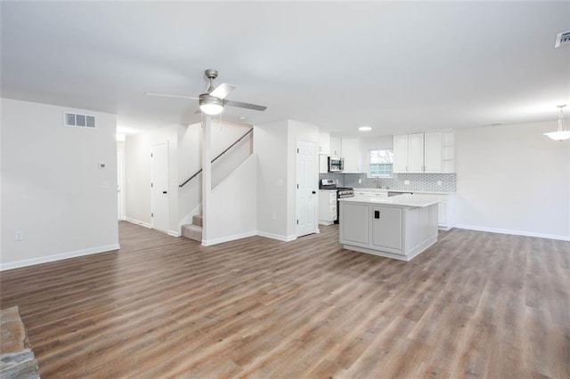 kitchen with white cabinetry, a center island, ceiling fan, backsplash, and appliances with stainless steel finishes