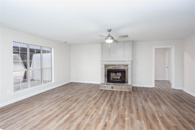 unfurnished living room featuring ceiling fan, light hardwood / wood-style flooring, and a stone fireplace