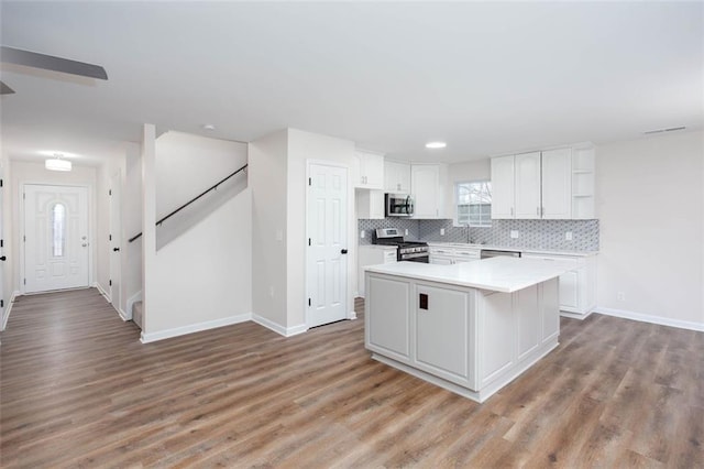 kitchen with stainless steel appliances, white cabinetry, a center island, and light wood-type flooring