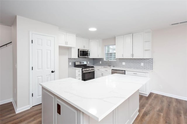 kitchen with stainless steel appliances, a kitchen island, and white cabinetry