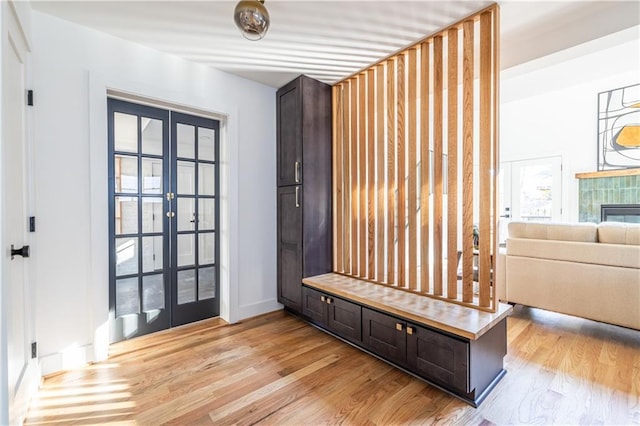 mudroom featuring light hardwood / wood-style flooring, a tile fireplace, and french doors