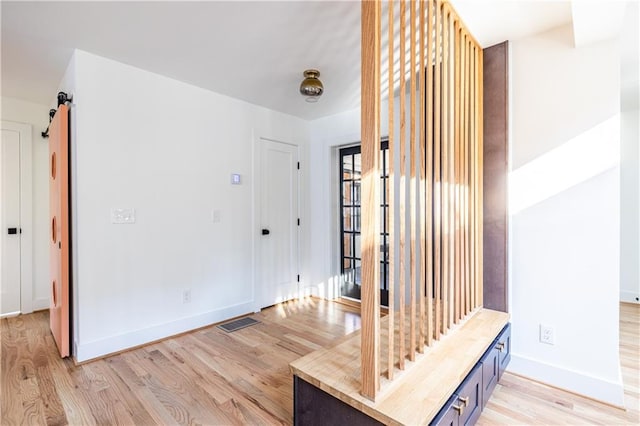 hallway with light wood-type flooring and a barn door