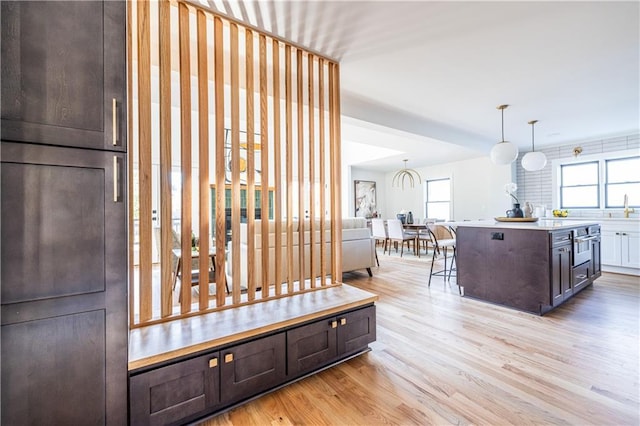 interior space with a breakfast bar, a center island, oven, light hardwood / wood-style flooring, and decorative light fixtures