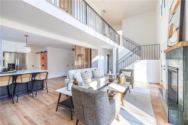 living room featuring light wood-type flooring, a fireplace, and a high ceiling