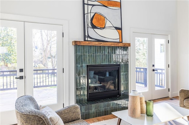 doorway to outside featuring hardwood / wood-style flooring, a tile fireplace, and french doors