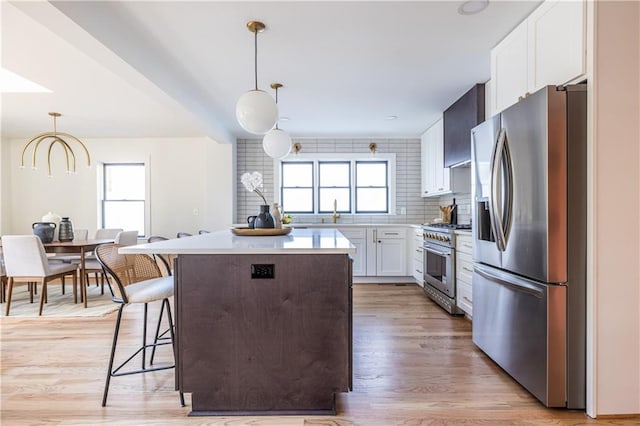 kitchen featuring tasteful backsplash, white cabinetry, hanging light fixtures, and appliances with stainless steel finishes