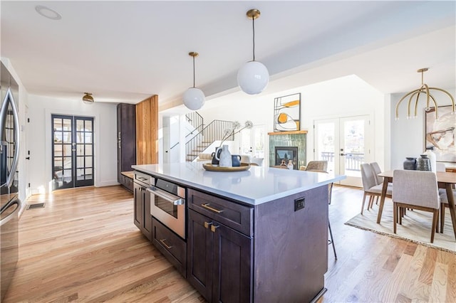 kitchen featuring french doors, light hardwood / wood-style flooring, oven, decorative light fixtures, and a kitchen island