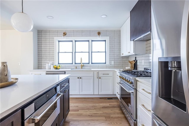 kitchen featuring appliances with stainless steel finishes, white cabinetry, hanging light fixtures, and sink