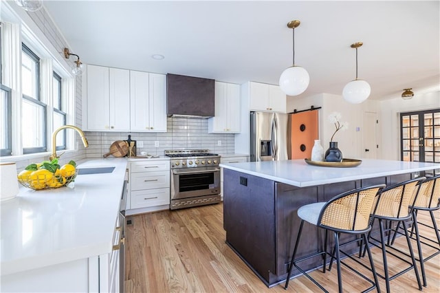 kitchen with wall chimney exhaust hood, a center island, white cabinetry, and stainless steel appliances