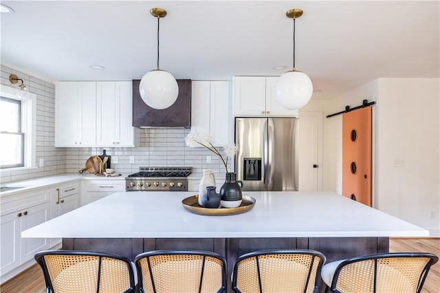 kitchen with stainless steel fridge, tasteful backsplash, a barn door, range, and a center island