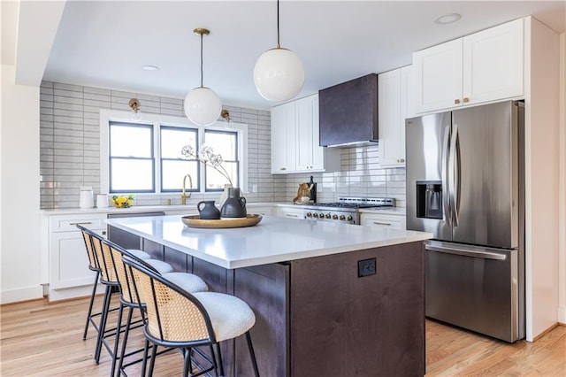 kitchen with white cabinetry, wall chimney range hood, and appliances with stainless steel finishes