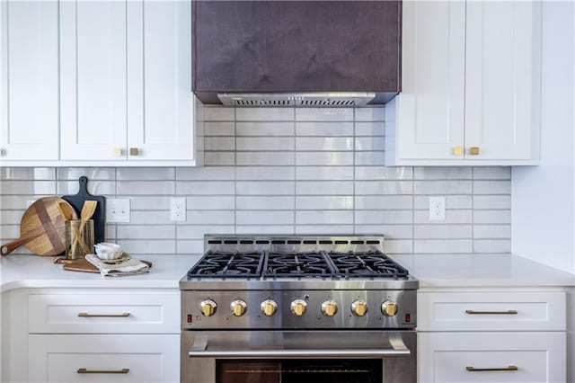 kitchen featuring tasteful backsplash, wall chimney range hood, white cabinetry, and high end stainless steel range oven