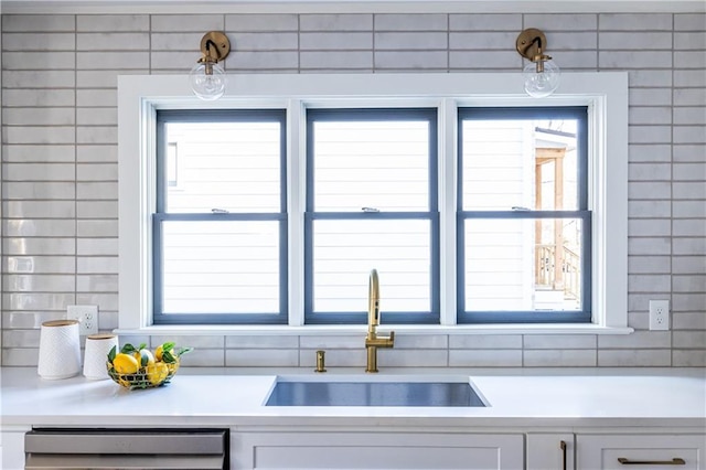 kitchen with dishwasher, white cabinetry, and sink