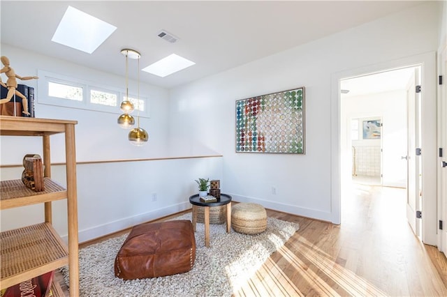 living area featuring light hardwood / wood-style floors and a skylight