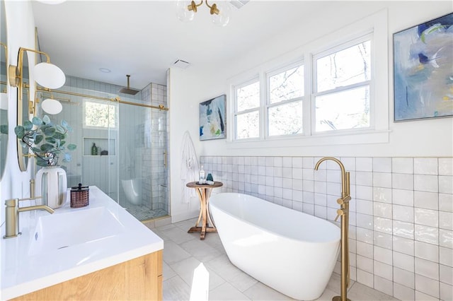 bathroom with vanity, plus walk in shower, a healthy amount of sunlight, and tile walls